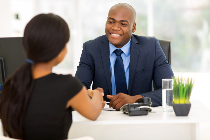 Man sitting behind a desk shaking a woman's hand