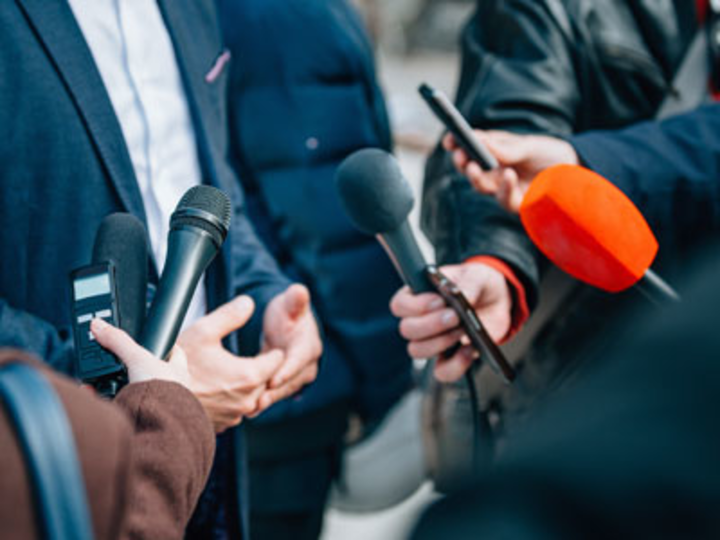 People holding up microphones to a person