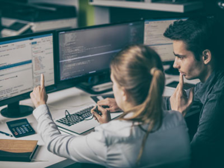 A man and woman looking at a computer screen as the woman points to the screen