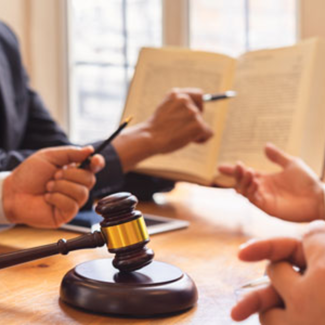 People pointing and discussing a book with a gavel on the table