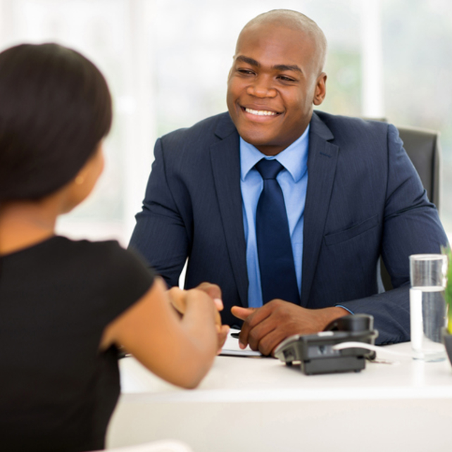 Man sitting behind a desk shaking a woman's hand